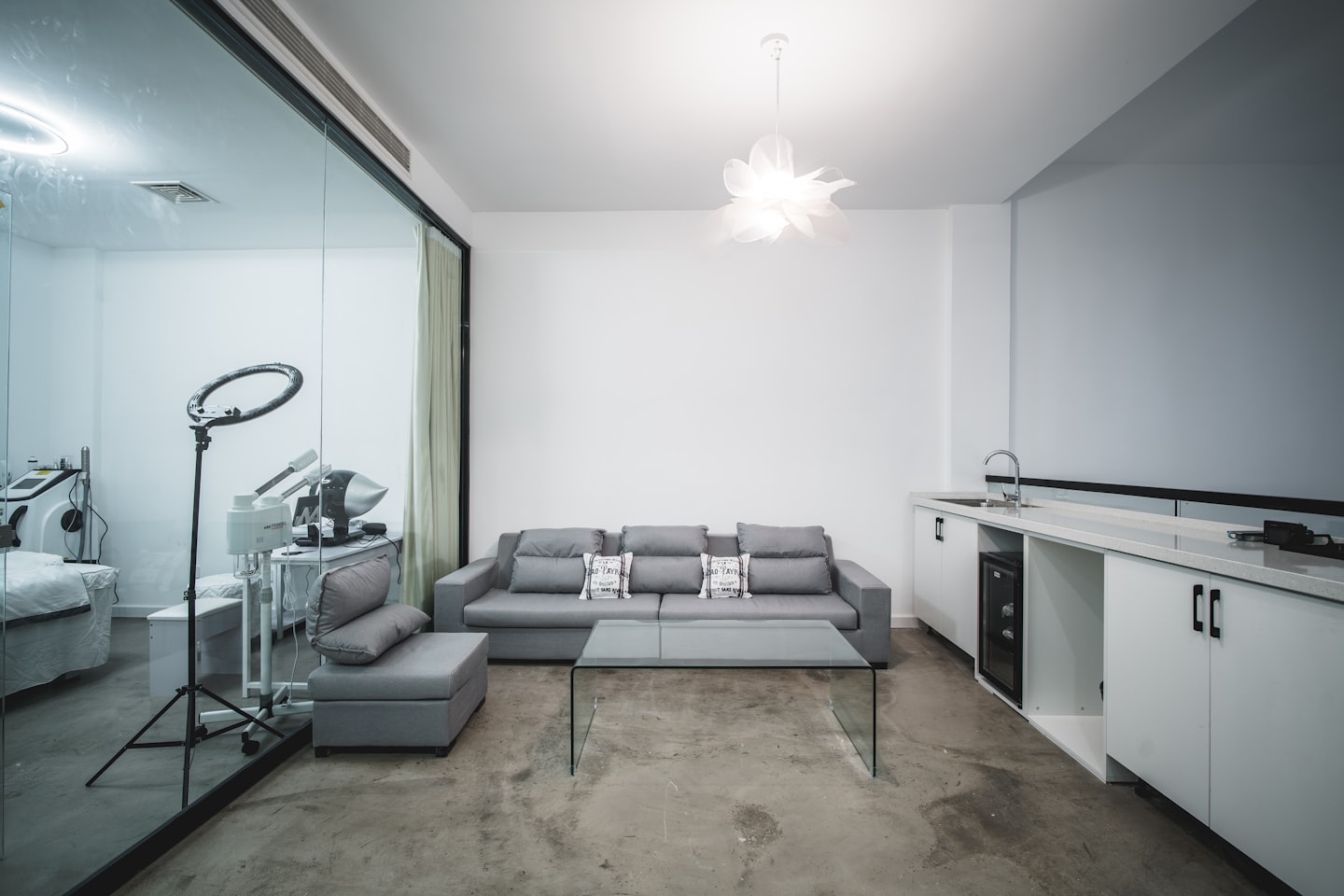 Moderner Wartebereich mit grauem Sofa und Blick auf den Behandlungsraum.